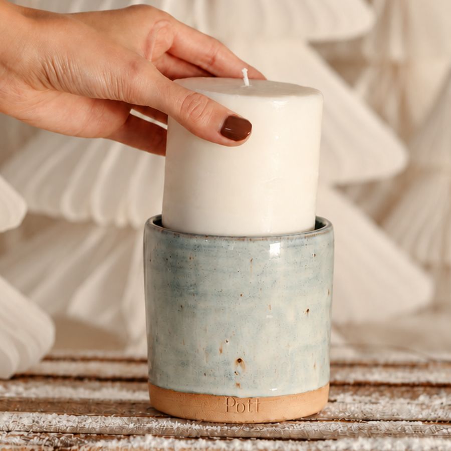 A hand lifting a candle refill out of a navy Pott